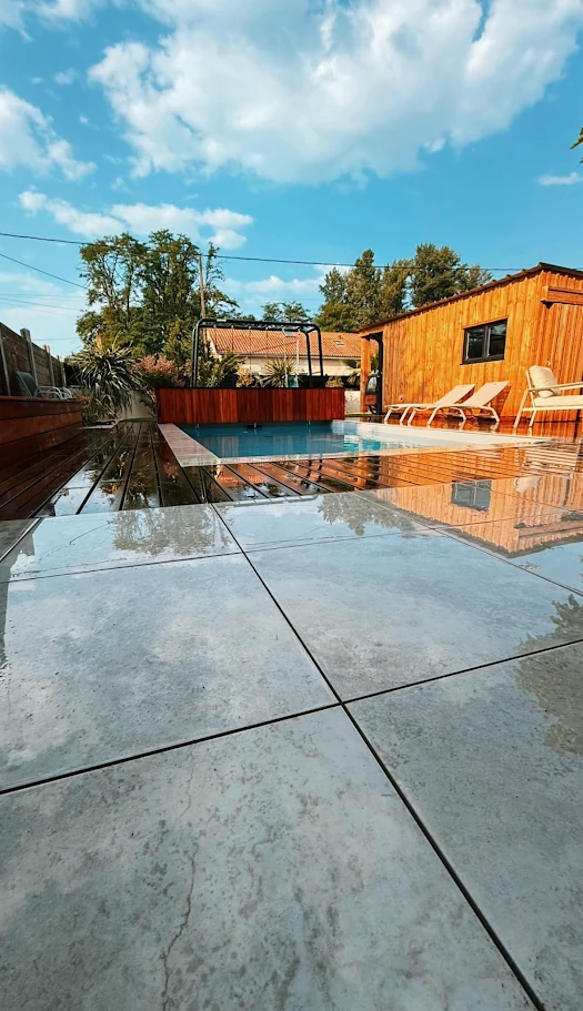Piscine bordée d'une terrasse minérale avec bâtiment en bardage bois