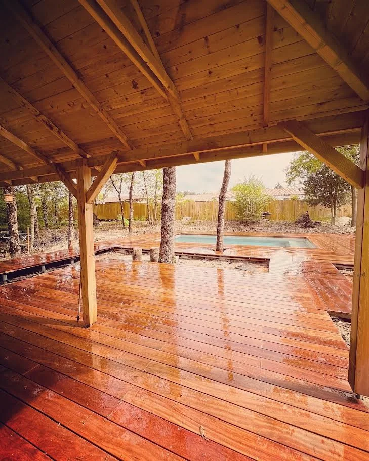 Terrasse en bois sous une pergola avec vue sur la piscine